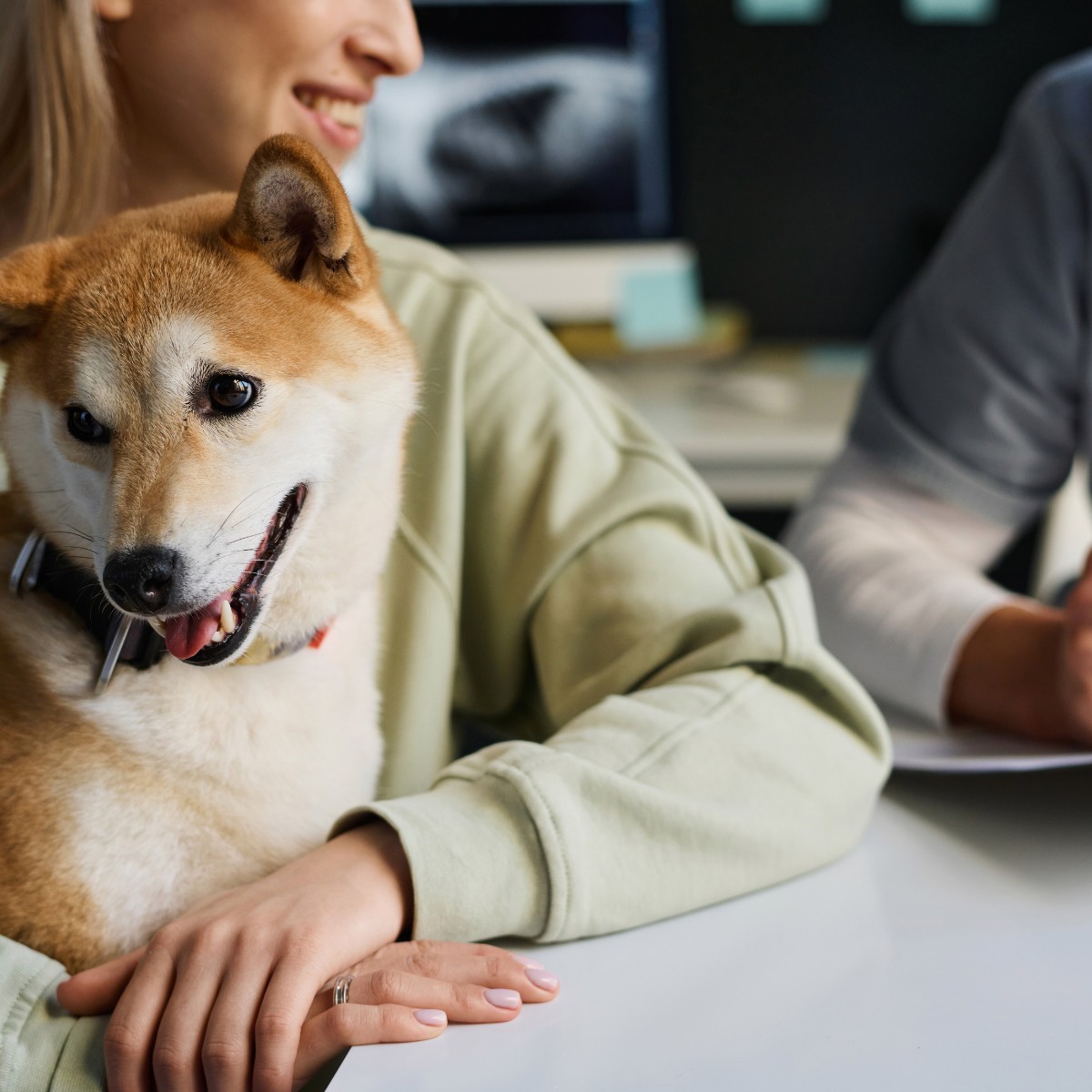 A woman and her dog are seated together at a table